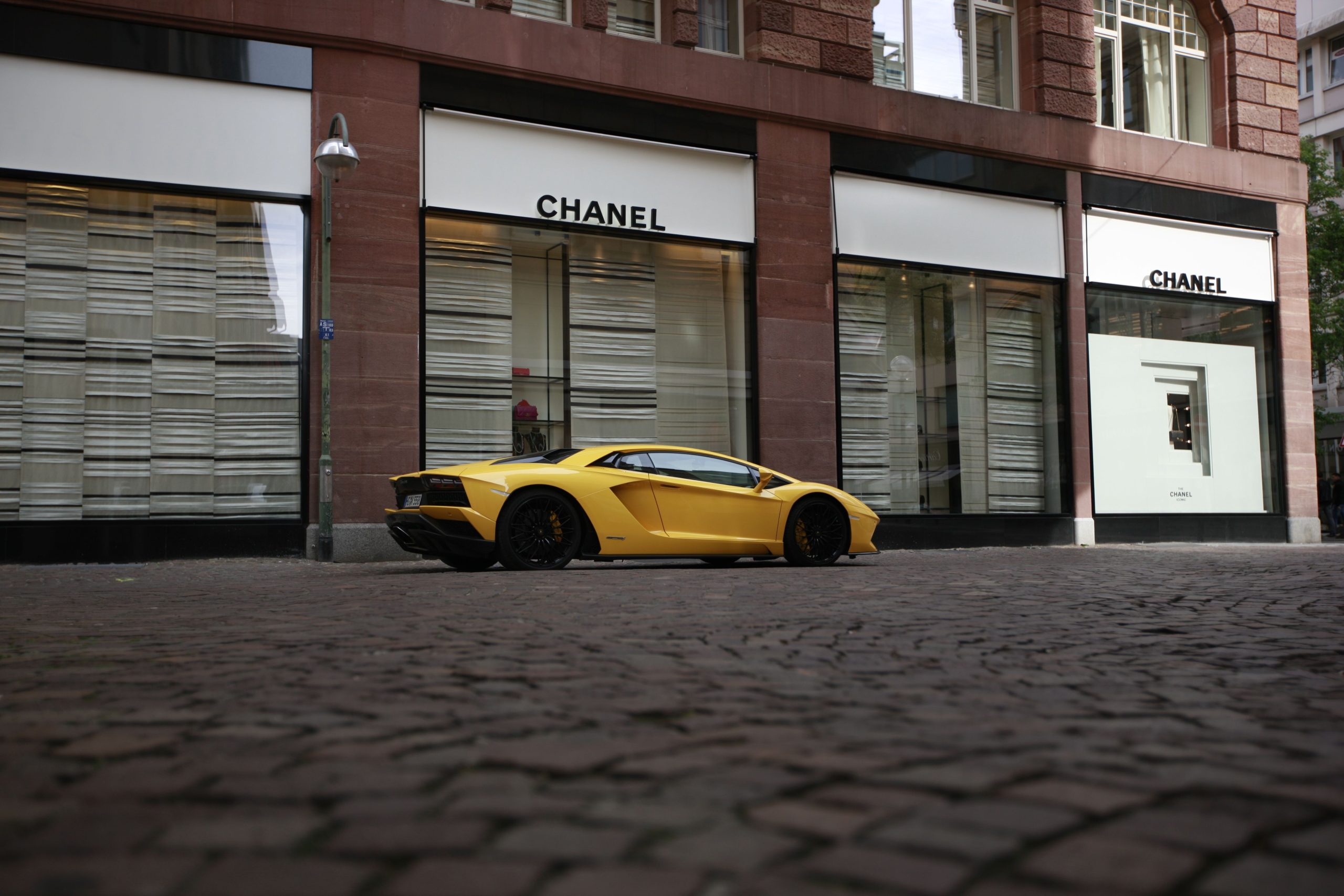 Voiture sport jaune devant boutique Chanel luxe